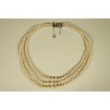 A GRADUATED TRIPLE STRAND CULTURED PEARL NECKLACE, the 18ct white gold and platinum clasp collet set