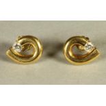A PAIR OF DIAMOND SET EAR STUDS, the 18ct gold shaped loops tension set with a brilliant cut stone