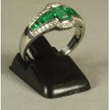 AN EMERALD AND DIAMOND DRESS RING, the step cut central emerald flanked by ten graduated baguette