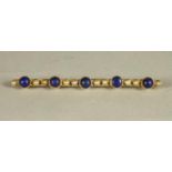 A LATE VICTORIAN BROOCH, the open bars centred by five open back collet set polished lapis lazuli