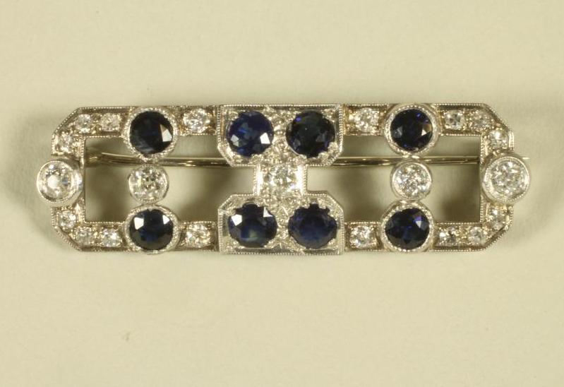 AN ART DECO SAPPHIRE AND DIAMOND BROOCH of oblong form, the knife edge bars  open back collet set