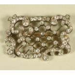 AN EDWARDIAN DIAMOND SET OPEN TRELLIS WORK PANEL BROOCH of rococo form, pave and open back collet