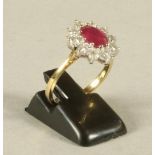 A RUBY AND DIAMOND CLUSTER RING, the oval cut ruby claw set to a border of ten brilliant cut