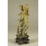 A CHINESE SOAPSTONE FIGURE, 20th century, carved as a young lady holding aloft a basket of