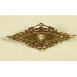 A LATE VICTORIAN 15CT GOLD BROOCH, the eliptical panel centred by a gypsy set diamond within