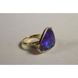A CONTEMPORARY BLACK OPAL RING, the rounded triangular stone close back set to open shoulders and