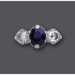 A THREE STONE SAPPHIRE AND DIAMOND RING, the central oval facet cut sapphires flanked by two claw