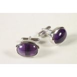 A PAIR OF AMETHYST CUFFLINKS, the oval cabochon polished stones open back collet set in a plain