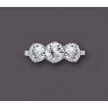 A THREE STONE DIAMOND RING, the central brilliant cut stone of approximately 1.20cts claw set and