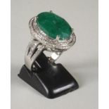 AN EMERALD AND DIAMOND CLUSTER RING, the oval cut emerald of approximately 8cts, claw set to a