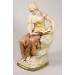 A ROYAL DUX PORCELAIN FIGURE, c.1900, of a young maiden wearing a draped top and skirt, reading a