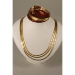 A 1960's 18K GOLD TRIPLE STRAND NECKLACE AND MATCHING BRACELET, with matt fluid brick links, stamped