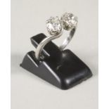 A TWO STONE DIAMOND RING, each stone of approximately 0.70cts, claw set in a crossover setting to