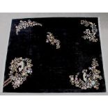 A CHINESE WASHED AND FRINGED BLACK GROUND CARPET with central polychrome floral spray and similar