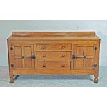 AN ADZED OAK SIDEBOARD by Robert Thompson, the moulded edged top with ledge back, three central