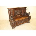 A LATE VICTORIAN CARVED OAK SETTLE, the triple panelled back depicting St George slaying the