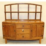 AN ARTS AND CRAFTS STYLE OAK SIDEBOARD, 20th century, of canted bow form, the arched open panel back