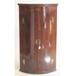 A GEORGIAN MAHOGANY CORNER CUPBOARD, late 18th century, of quadrant form with chequer stringing,