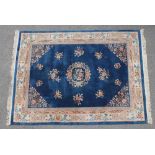 A CHINESE WASHED AND FRINGED CARPET, the navy blue field with polychrome floral sprandrels and