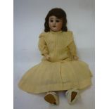 An S.F.B.J. bisque head doll with brown glass sleeping eyes, open mouth and teeth, brown mohair wig,