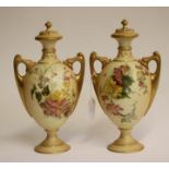 A PAIR OF ROYAL WORCESTER CHINA VASES AND COVERS, 1904, of two handled ovoid form on a low socle,