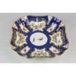 A Royal Worcester scalloped edged square dish decorated with hand painted panels of birds and