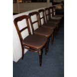 A set of six Victorian dining chairs with scroll carved backs, solid seats, on turned legs.