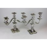 A pair of silver plated three-light candlesticks, with ornate, foliate and scrolled borders, on