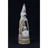 A 19th century Indian ivory carving of Buddha, enshrined in a dragon lattice covering, 17cm high