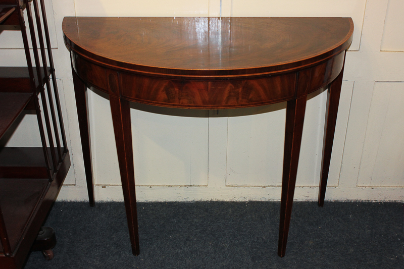 A cross banded and inlaid mahogany demi-lune card table with fold-over top and green baize lining,