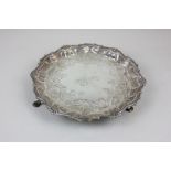 A George II silver card tray with embossed scroll detail and shell and scroll border, on pad feet,