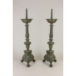 A pair of gilt metal pricket candlesticks with cast baluster stems and scroll decorated triform