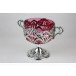 An Art Nouveau silver plated pedestal bowl with cranberry glass liner and floral embossed detail