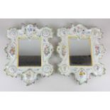 A pair of Italian mirrors with scroll and floral formed pottery frames, bevelled glass and