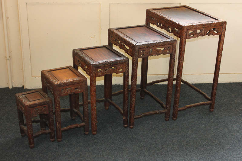 A nest of five Chinese hardwood tables, the sides and legs carved with grapevines, 46cm wide, (NC)