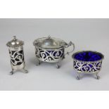 A George V  silver cruet set of mustard, salt and pepper with pierced scroll decoration on claw