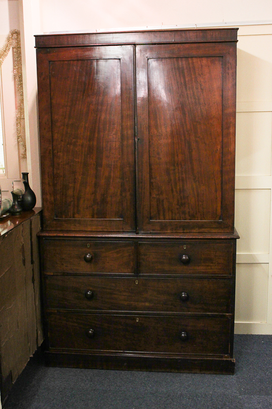 A George III mahogany press cupboard with panelled cupboards enclosing hanging rail, above two short