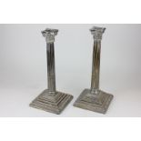 A pair of silver plated Corinthian column candlesticks on square stepped bases with egg and  dart