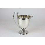 A George III silver cream jug, baluster shaped with sparrow beak pourer, plain body with lion crest,