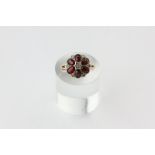 A garnet and diamond cluster ring set with six oval cut stones with rose diamonds between