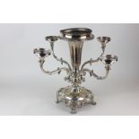 A silver plated table candlestick with central vase and four scroll branches, on base with scroll
