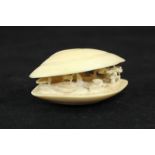 An early 20th century Japanese clam shell form netsuke carved with an interior agricultural scene,