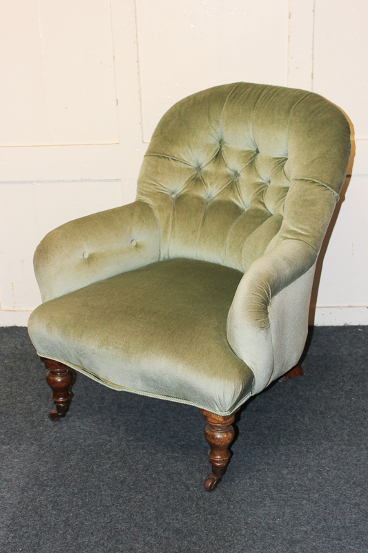 A Victorian green button upholstered armchair on turned legs and castors