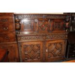 An oak court cupboard, with three carved panel top, on turned baluster supports, above two drawers