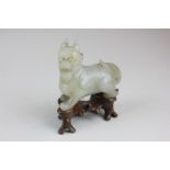 A Chinese carved mutton fat jade temple dog on hardwood stand, 7cm wide