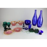 A collection of coloured glass tableware including a blue bowl, pair of green salts and a small