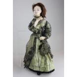 An Edwardian papier mache doll with painted face with fixed composite limbs, in period dress, 33cm