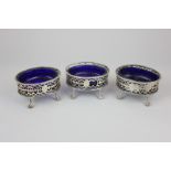 A set of three George III silver salts with gadroon borders, cutout scroll sides, on claw and ball