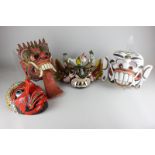 Four Balinese papier mache masks, all brightly decorated with fangs and pointed teeth