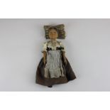 A carved wooden doll, possibly German, with jointed arms and legs, painted face and detailed costume